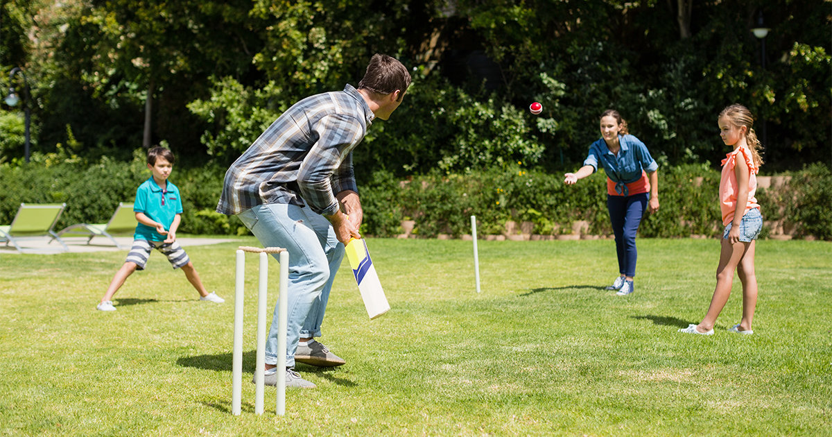 Family playing cricket in backyard
